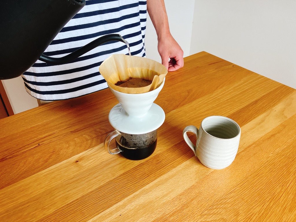 木製テーブルの上でコーヒーを注いでいる様子