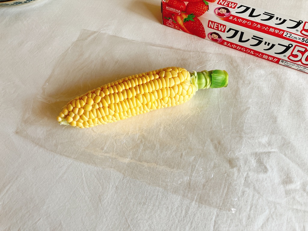 とうもろこしをラップに包んで電子レンジで温める準備
